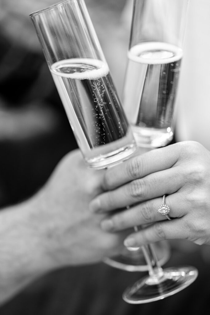 A couple toasting with champagne glasses during their engagement session.