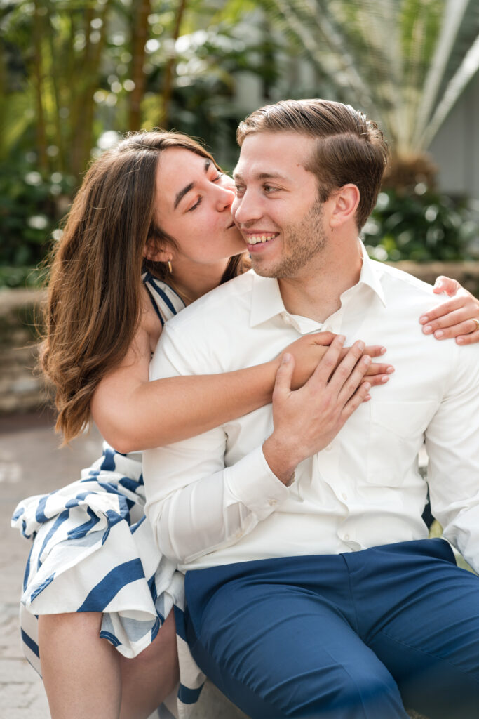 A bride to be kissing her future groom on the cheek during their engagement session at the Franklin Park Conservatory in Columbus, Ohio.